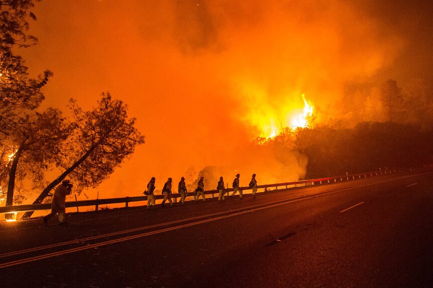 Cal Fire firefighters walk along Highway 20 as the Rocky fire burns near Clear Lake, California