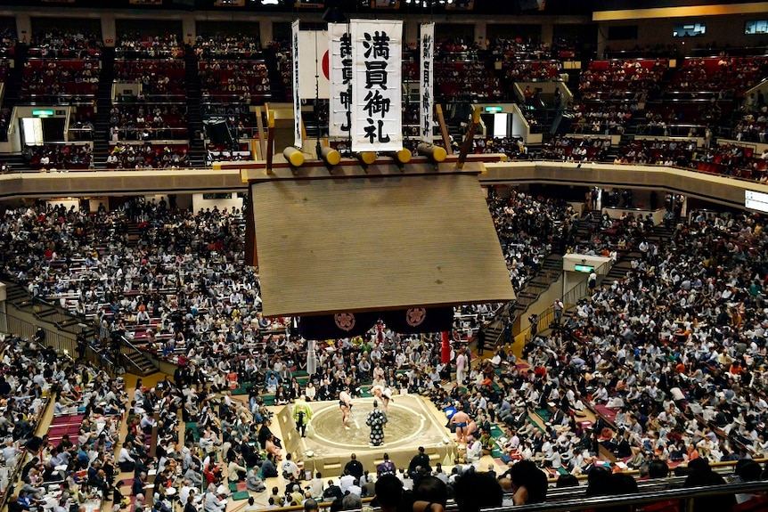 An arena with people watching a sumo event.