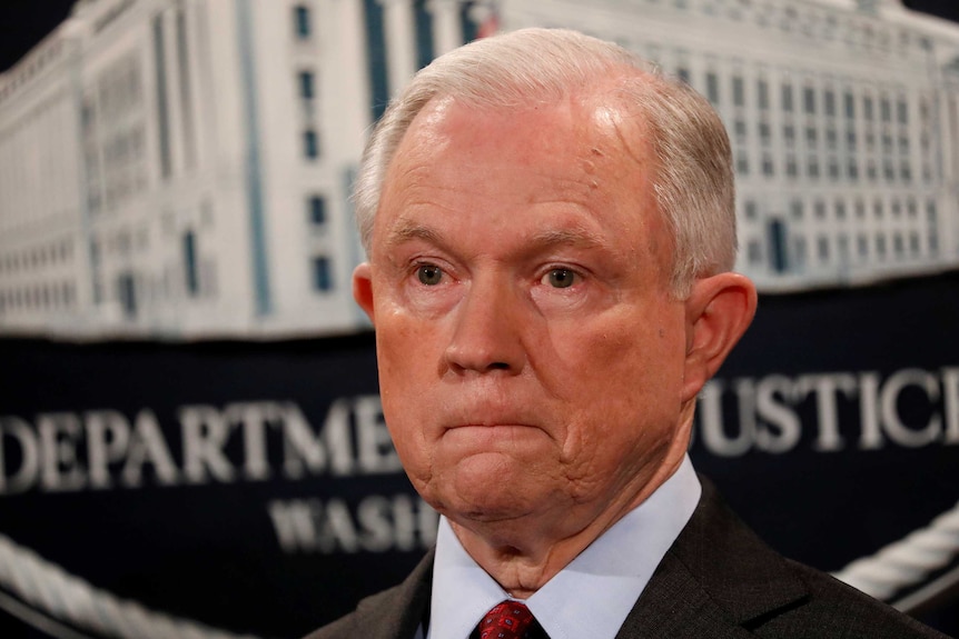 Tight headshot Jeff Sessions looking pensive against a Department of Justice backdrop