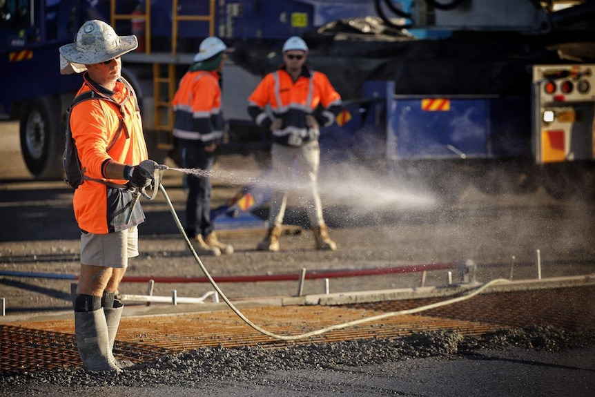 A worker hoses water during a concrete slab pour at a building construction site.