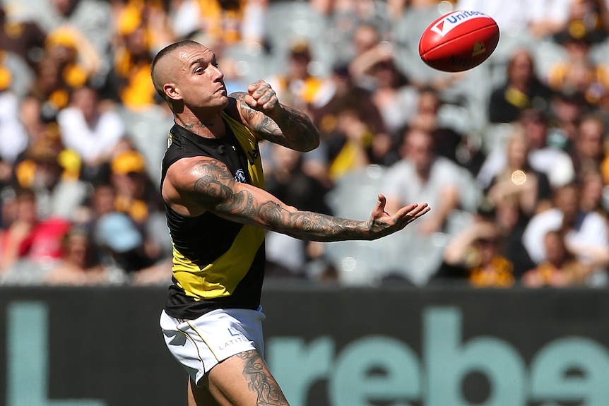 A Richmond AFL player hand balls with his left fist against Hawthorn at the MCG.