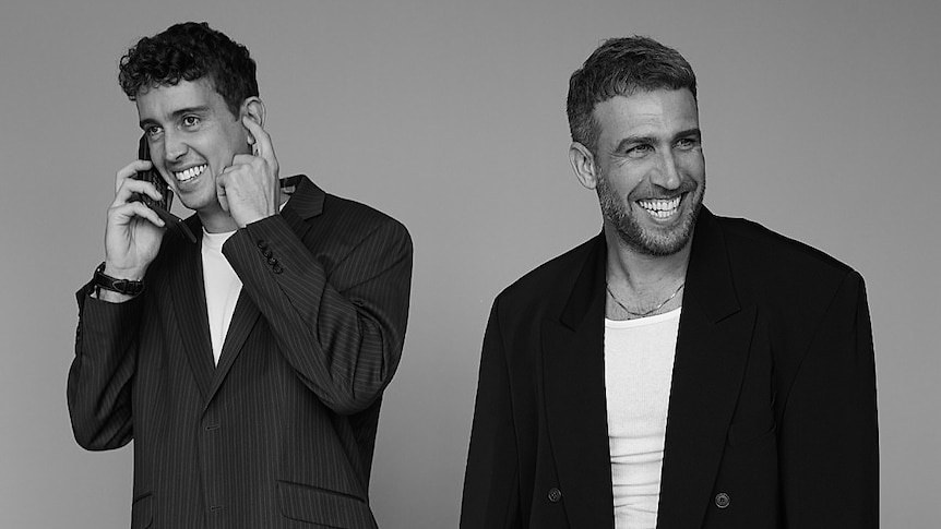 Black and white promo photo of Hugo and Jimmy from Flight Facilities smiling in suits