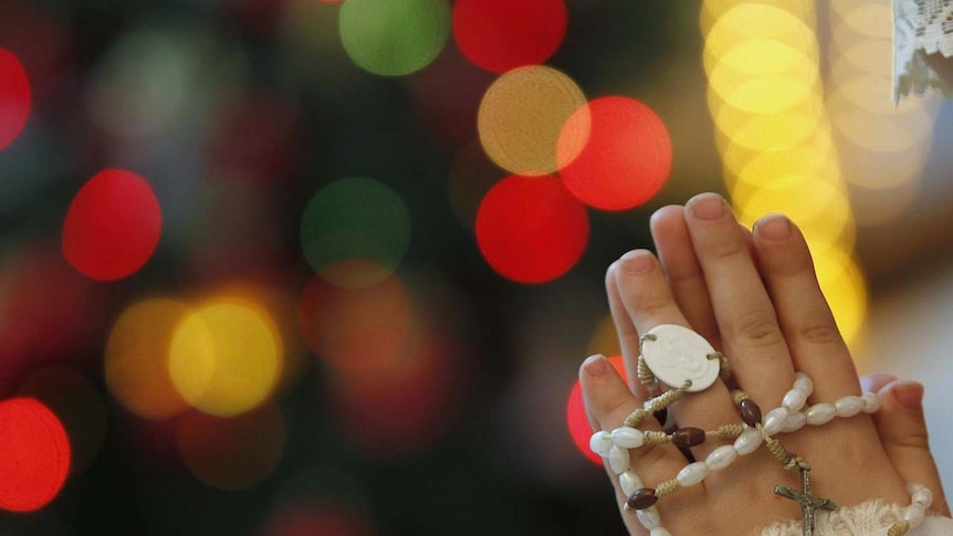 An Iraqi girl prays with a rosary