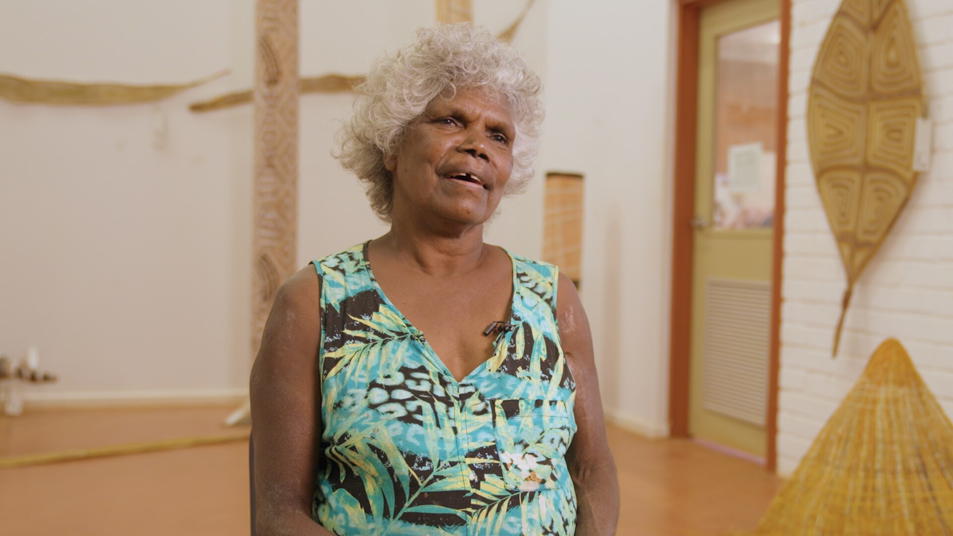 Freda Wayartja Ali, a Burarra woman in her 60s with short curly grey hair, wearing a pale blue singlet in a gallery.
