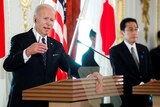 Joe Biden speaking at a press conference behind a lectern with Fumio Kishida in the background.
