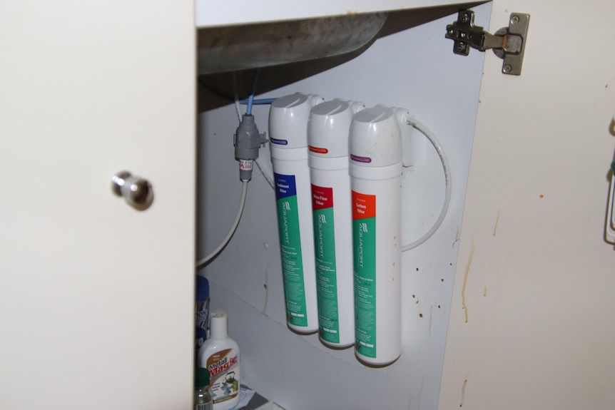 Three pumps under a sink attached to a wall.