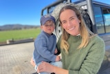 Boy and woman smiling at camera while standing in front of a ute 