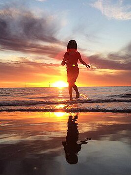 A child plays on the beach as the sun sets.