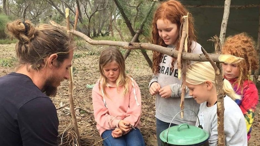 Steve Aldridge showing four girls how to make a fire in story about how 'wild schools' can help kids understand nature.