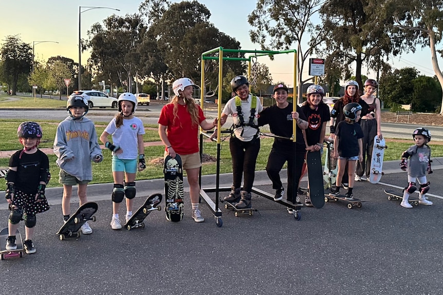 a group of girls with skateboards and helmets flank a woman in a skate frame