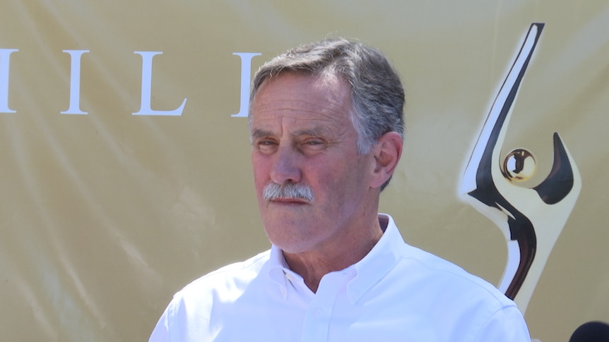 A close-up picture of a man wearing a white, collared shirt.