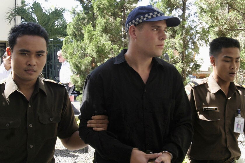 Matthew Norman walks handcuffed between two Indonesian policemen