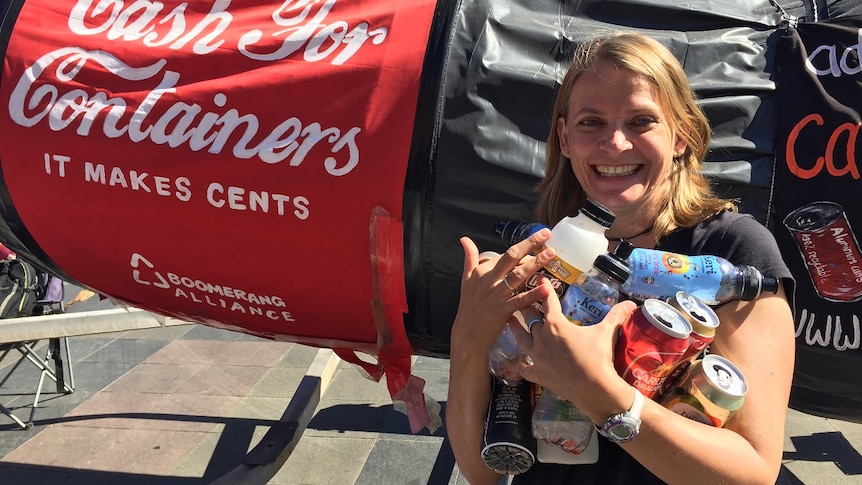 Woman holding rubbish standing in front of a three-metre soft drink bottle