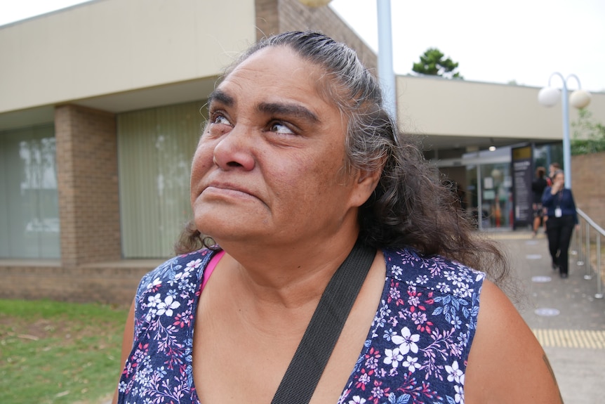 Close-up of woman's face standing in front of courthouse.