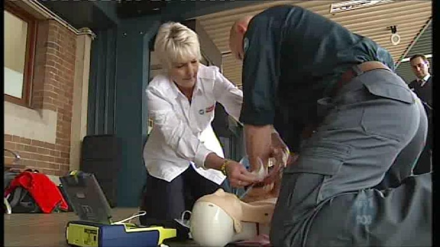 Two people test a defibrillator on a dummy