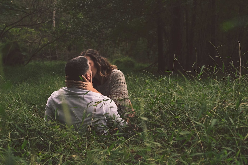 Couple kissing in long grass pictured in story about eco-friendly sex