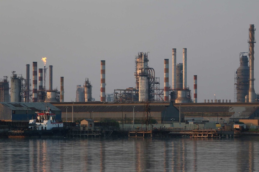 Chimneys and buildings are visible across a river at the Abadan oil refinery.