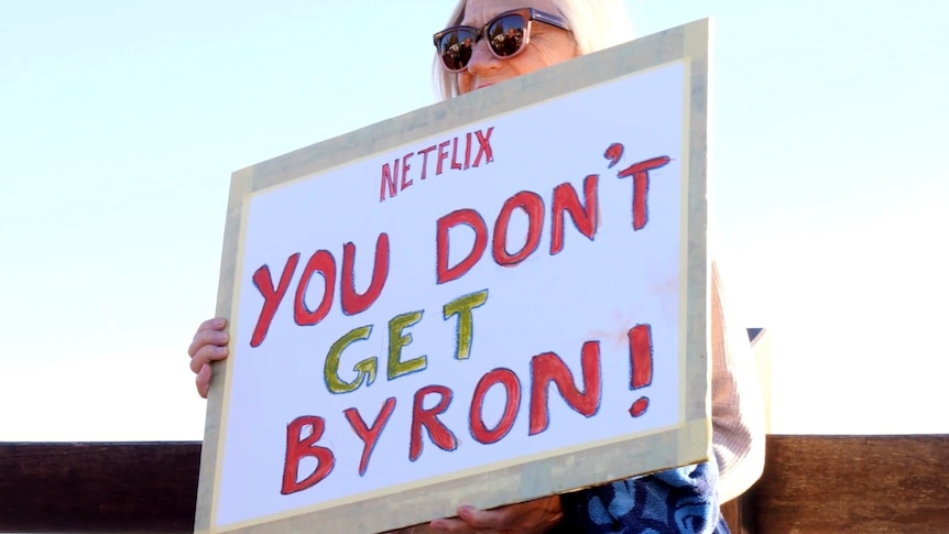 A woman holds a sign saying Netflix you don't get Byron