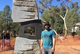Man stands in front of stone sculpture