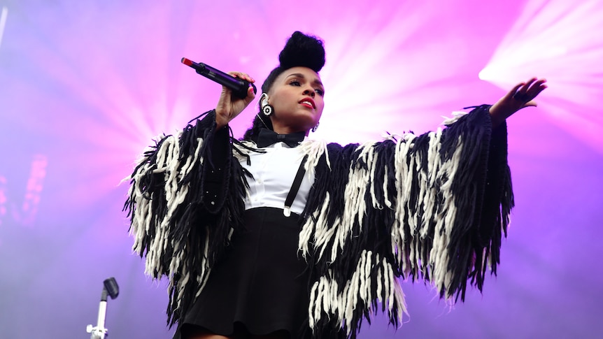 Janelle Monae on stage against a pink background