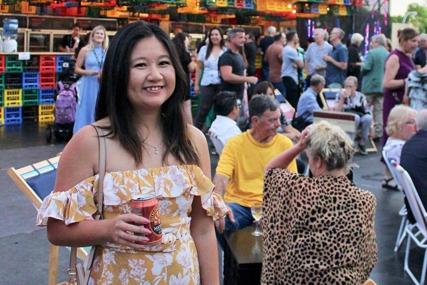 A woman holding a ginger beer at a food festival