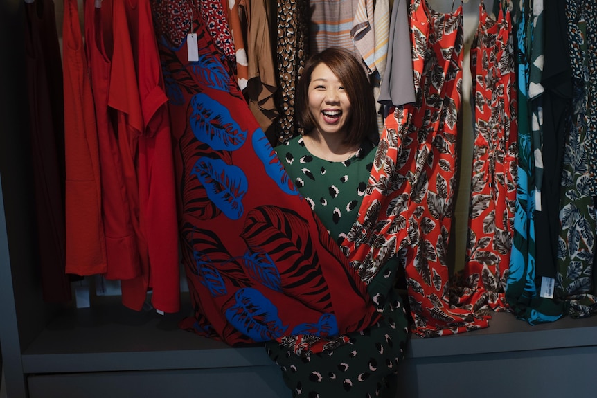 Young woman surrounded by fabric looks happy 