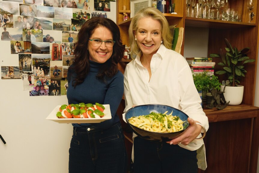 Bridget McKenzie and Annabel Crabb holding plates of food after filming Kitchen Cabinet