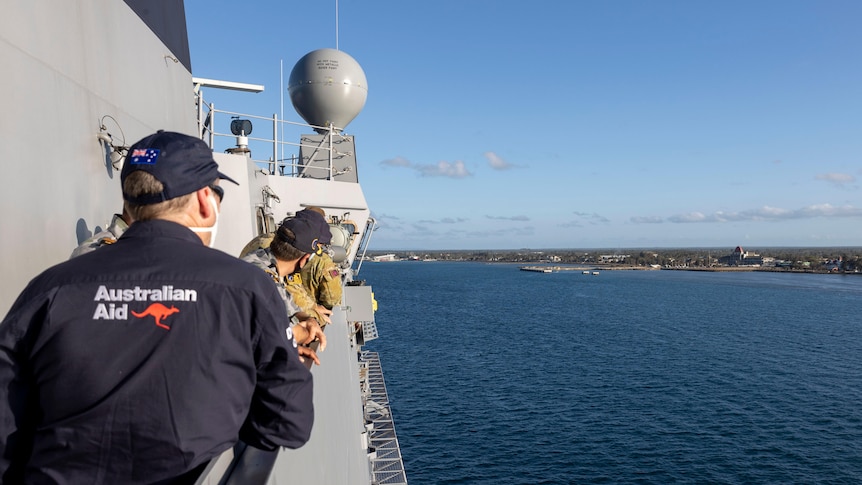 Naval and aid officers look from HMAS Adelaide out to Tonga