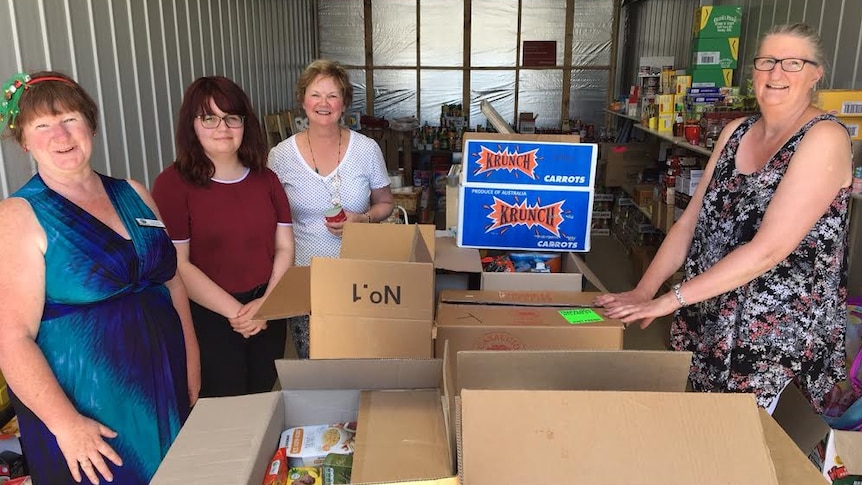 A group of people standing around some food hamper boxes.