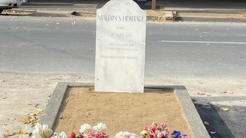 a fake tombstone sticks out of a planter box.