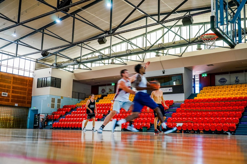 People play basketball in an empty stadium.