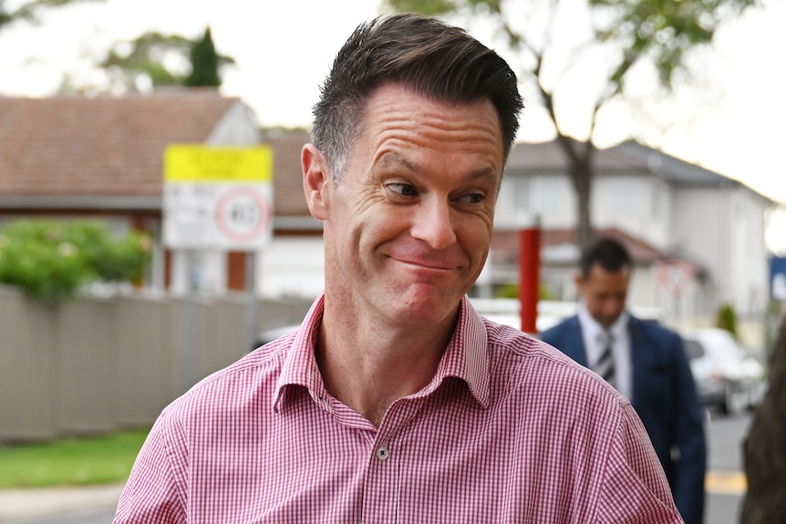 Man dressed in pink shirt holding up hands