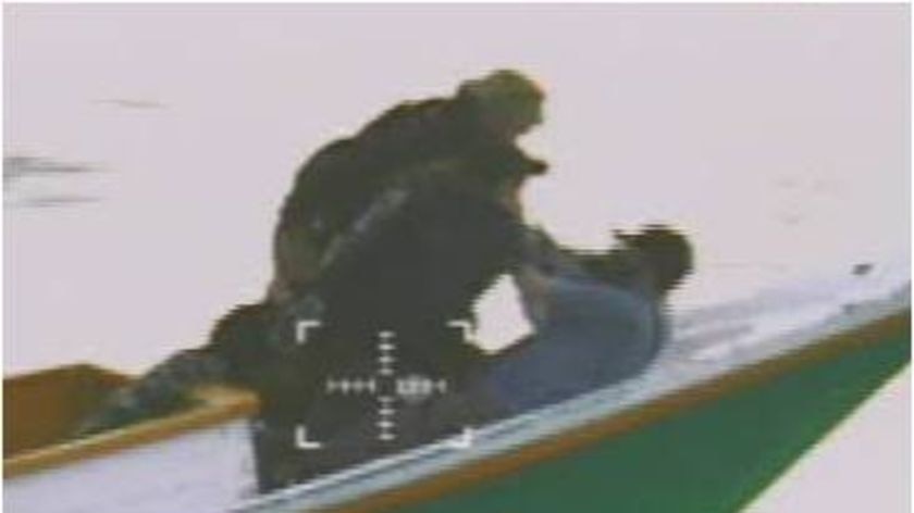 Australian Navy personnel wrestle with an asylum seeker allegedly holding a lighter.