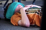 child lies on floor with facecloth over face