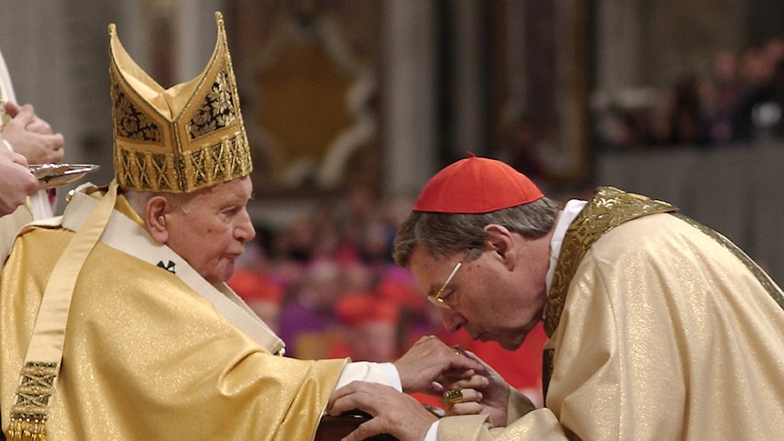 John Paul II holds out his hand and George Pell kisses it at a ceremony in the Vatican.