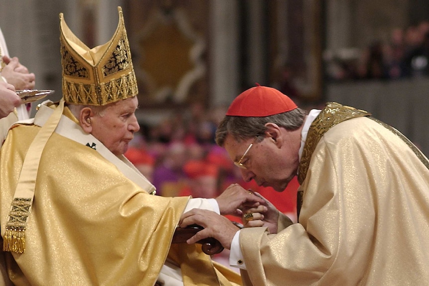 John Paul II holds out his hand and George Pell kisses it at a ceremony in the Vatican.