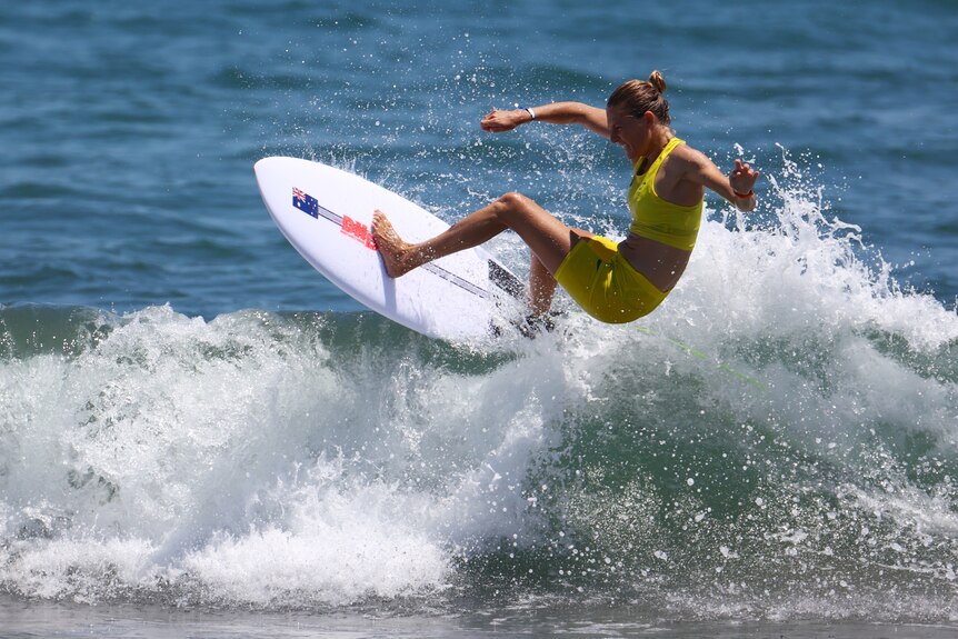A female surfer riding a wave at Tsurigasaki Surfing Beach in Japan.