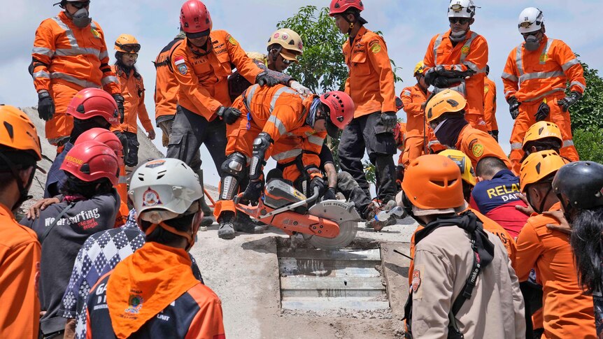 Rescuers use a saw as they try to recover the body of an earthquake victim from under the rubble.