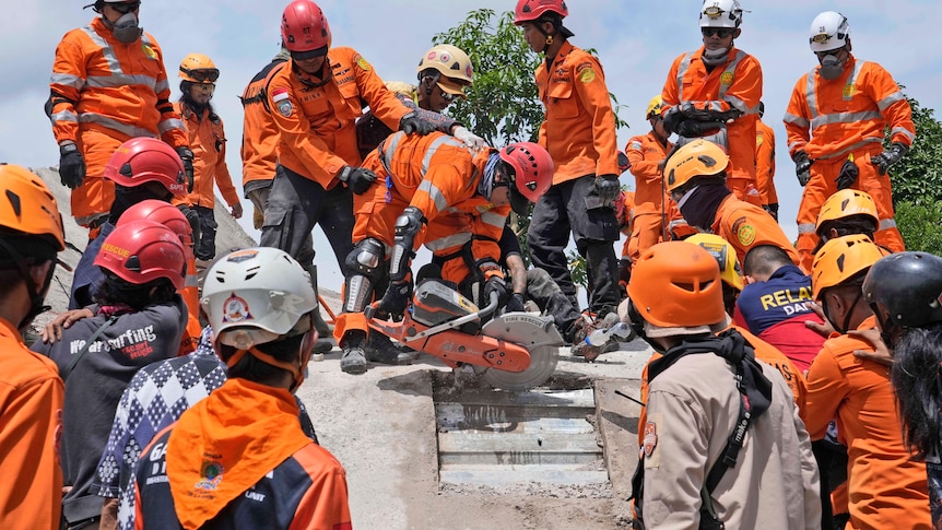 Rescuers use a saw as they try to recover the body of an earthquake victim from under the rubble.