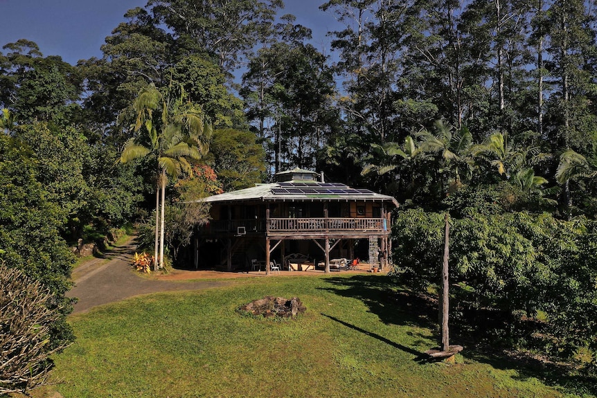 A large building sits nestled into a hillside surrounded by trees