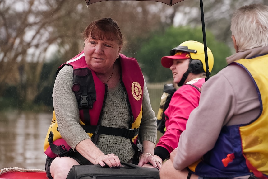 Une femme sur un bateau avec deux autres personnes portant des gilets de sauvetage