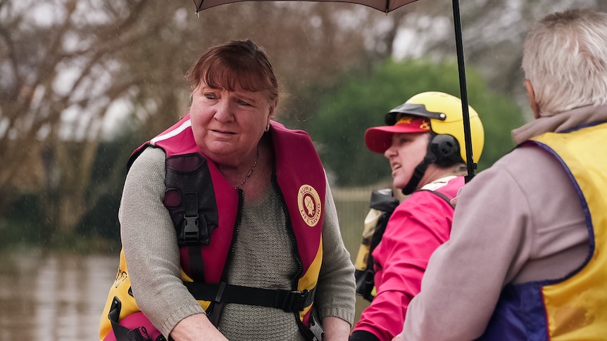 A woman on a boat with two other people with life jackets on