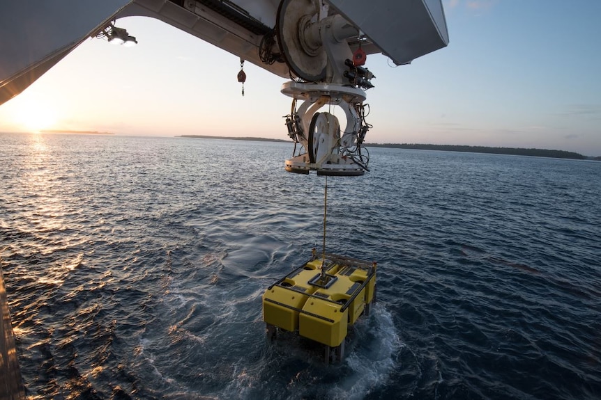 A winch pulling a yello Remote Operated Vehicle from the sea