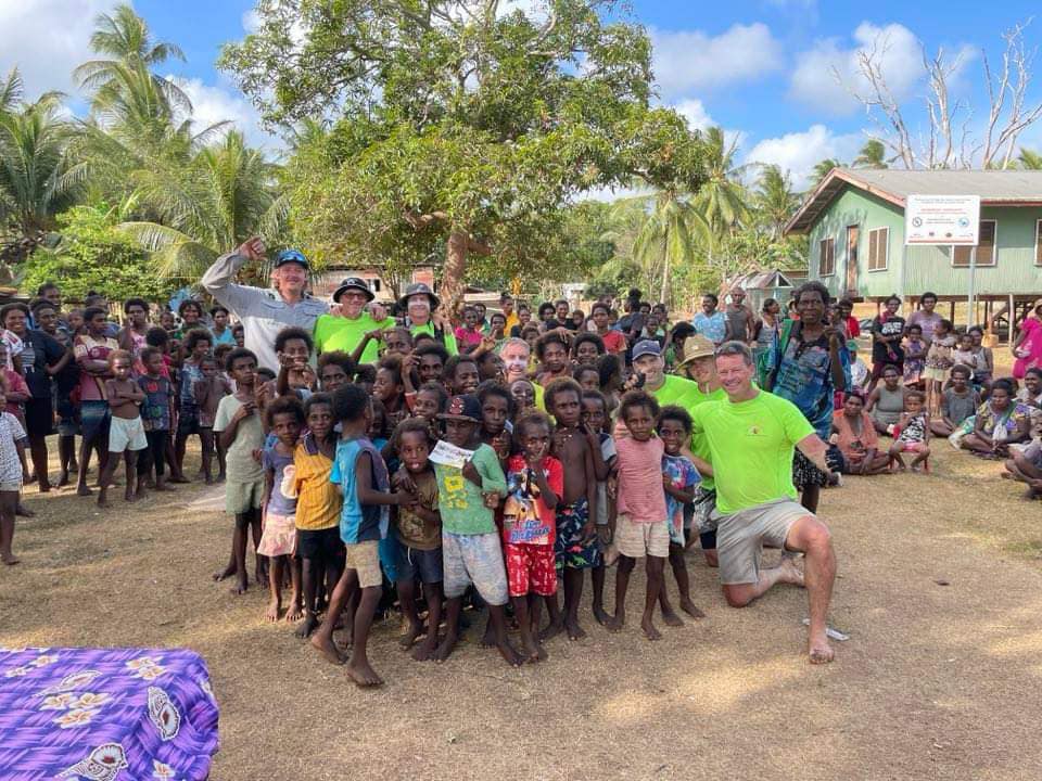 Two rowers meet with a large group of Papua New Guinea residents.