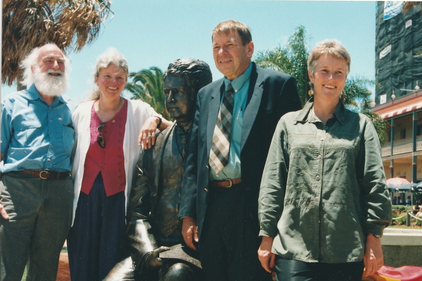 Four people stand either side of a statue while smiling