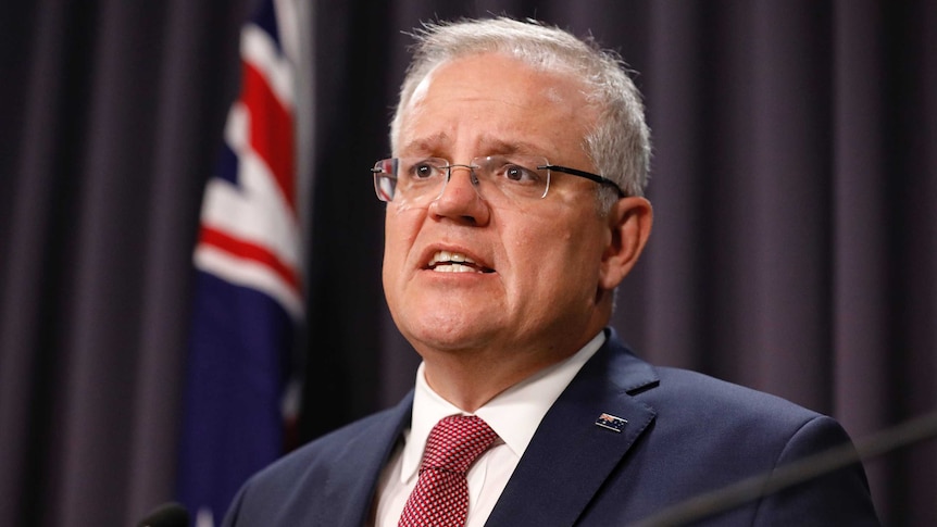 Mr Morrison is standing behind a lectern with an Australian flag in the background. He's mid sentence.