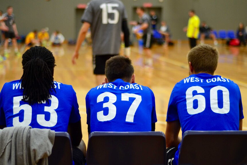 Handball players sit on the sidelines and watch their teammates play at the national championships in Geelong.