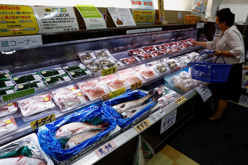 一名女士正在日本超市海鲜档口挑选商品