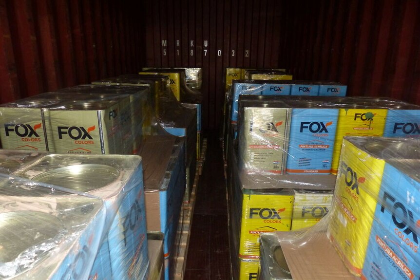 Pallets of tins labelled Fox in a shipping container.