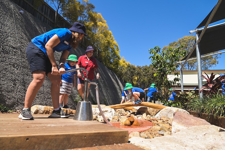 Educator Cat Marios plays with the children in the riverbed of new playground.